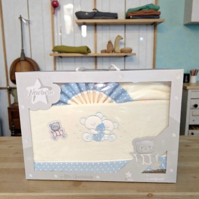 Conjunto de roupa de bebé em embalagem branca com detalhes de ursinhos e padrão azul com estrelas.