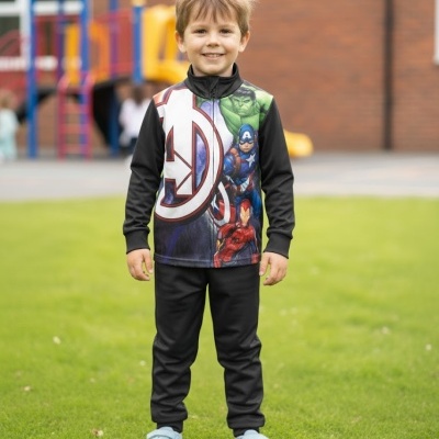 Camisola de criança preta com estampado Avengers e calças pretas em relvado com parque infantil ao fundo