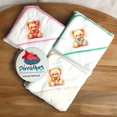 Toalhas infantis brancas com ursinhos coloridos sobre superfície de madeira