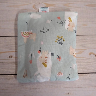 Almofada com padrão de animais e flores sobre superfície de madeira clara