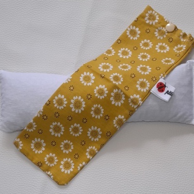 Estojo amarelo com flores brancas sobre almofada branca