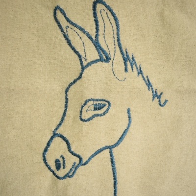 Desenho bordado da cabeça de um burro em tecido bege
