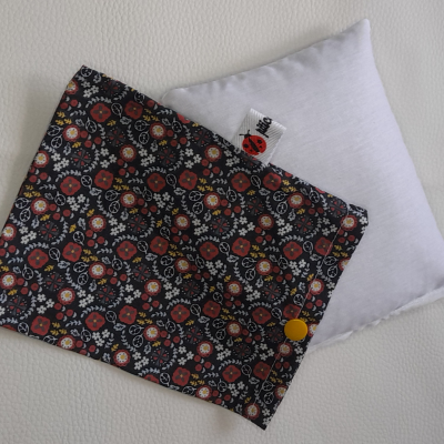 Almofada branca com capa preta de padrão floral colorido e botão amarelo