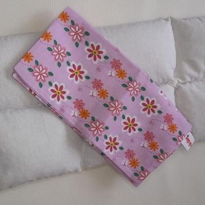 Três almofadas bege com bolsa rosa florida por cima