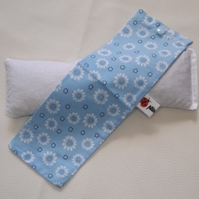 Almofada branca com capa azul claro estampada com flores brancas e pretas.