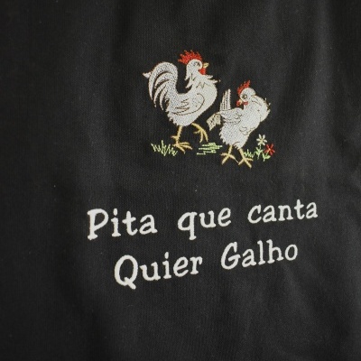 Tecido preto com estampa bordada de dois galos e texto branco