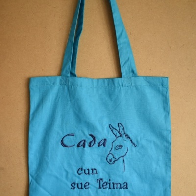 Saco de tecido azul com bordado roxo de cabeça de burro e texto