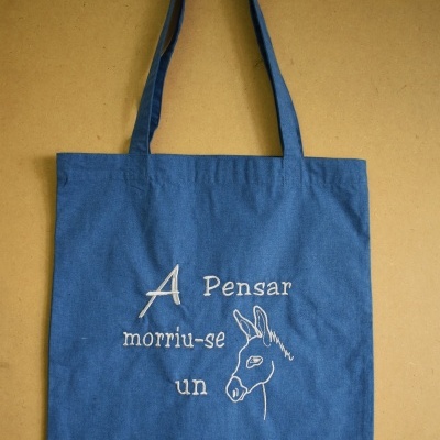 Saco de tecido azul com bordado branco de texto e desenho de burro