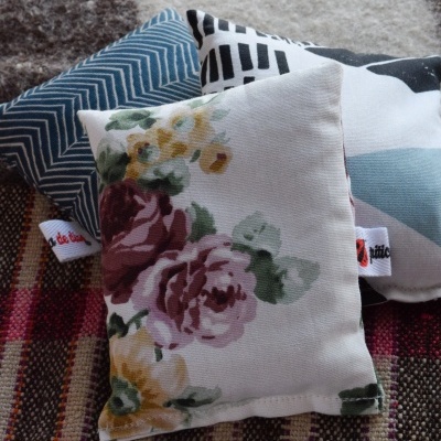 Três almofadas coloridas com padrões florais, geométricos e abstratos sobre tecido colorido