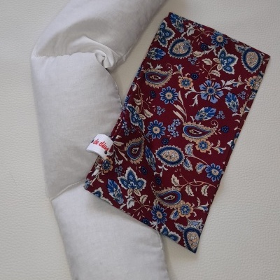 Almofada branca e saco térmico floral vermelho azul sobre superfície branca