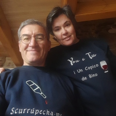 Duas pessoas com camisolas negras com texto e imagens relacionadas com vinho, em ambiente interior de teto de madeira