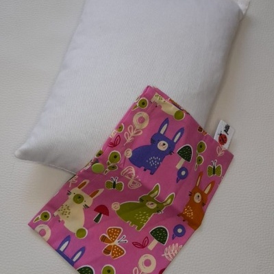 Almofada branca com capa rosa com coelhos e cogumelos coloridos