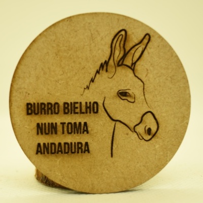 Disco redondo de madeira clara com gravura de um burro e texto gravado
