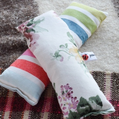Duas almofadas retangulares pequenas com padrões florais e riscas, em tapetes variados.