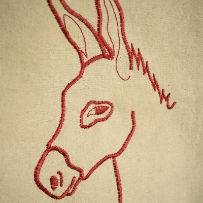 bordado cabeça de burro em linha vermelha sobre tecido bege