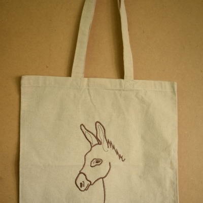 Saco de tecido bege com bordado de perfil de burro castanho