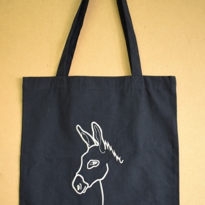 Saco de pano preto com desenho da cabeça de um burro em linha branca