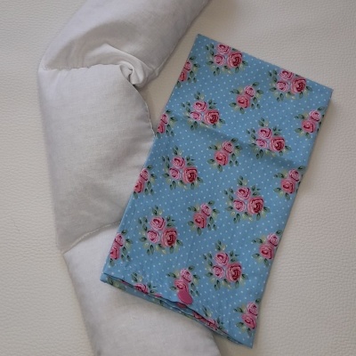 Travesseiro branco com capa azul floral dobrada