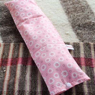 Almofada rosa com padrão de margaridas em tapete riscado