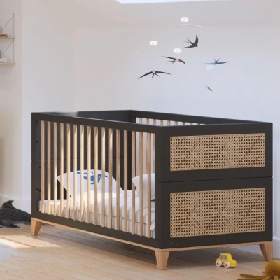 Berço de bebé de madeira preta com ripas claras e detalhes em rattan num quarto claro