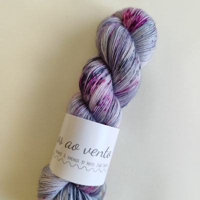 Novelo de lã multicolorido cinza, rosa e roxo com etiqueta branca sobre fundo branco