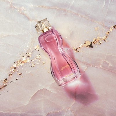 Frasco de perfume rosa em forma de corpo feminino com tampa transparente e detalhes dourados