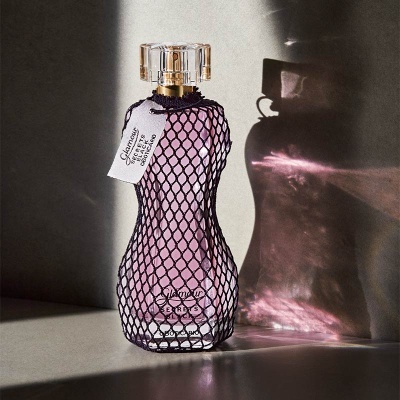 Frasco de perfume rosa sob luz com rede preta