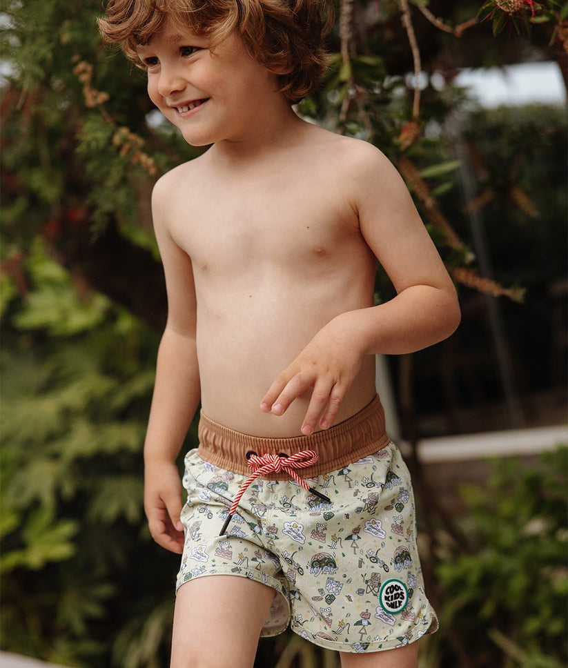 Calções de banho infantis com padrão colorido e cordão vermelho usados por criança