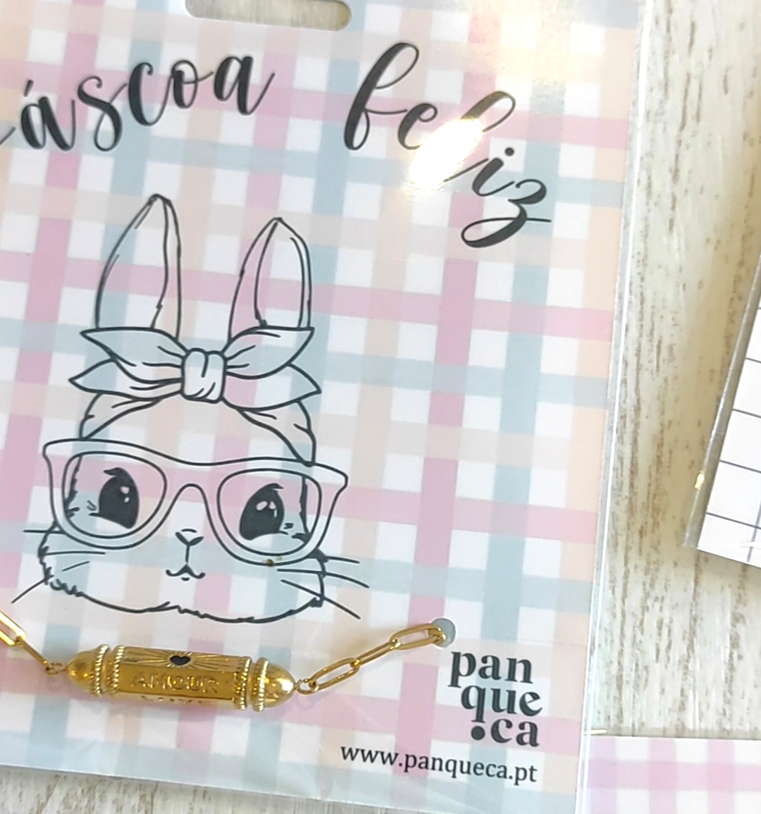 Cartão decorativo com coelho desenhado e pulseira dourada em embalagem