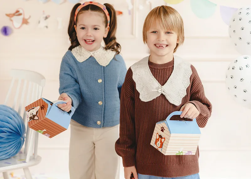 Crianças segurando caixas de papelão decorativas com alças.