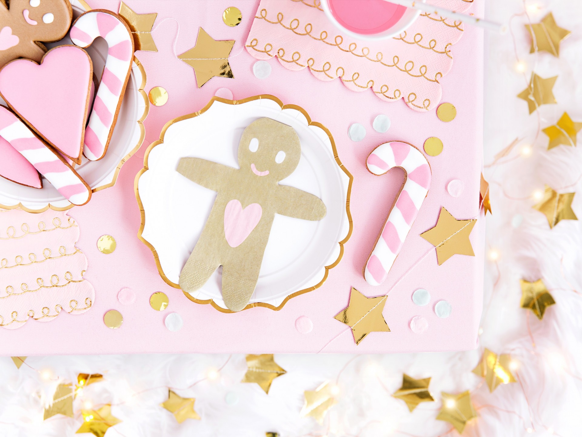 Biscoitos decorados em tema natalino, com cores rosa, branco e dourado, num cenário festivo.