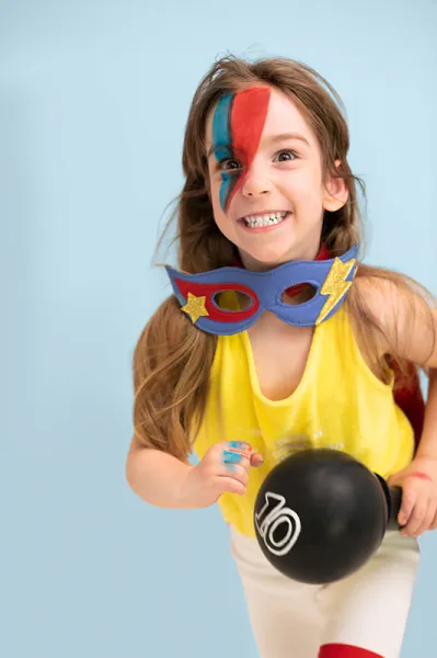 Criança com máscara azul segurando balão preto número 10