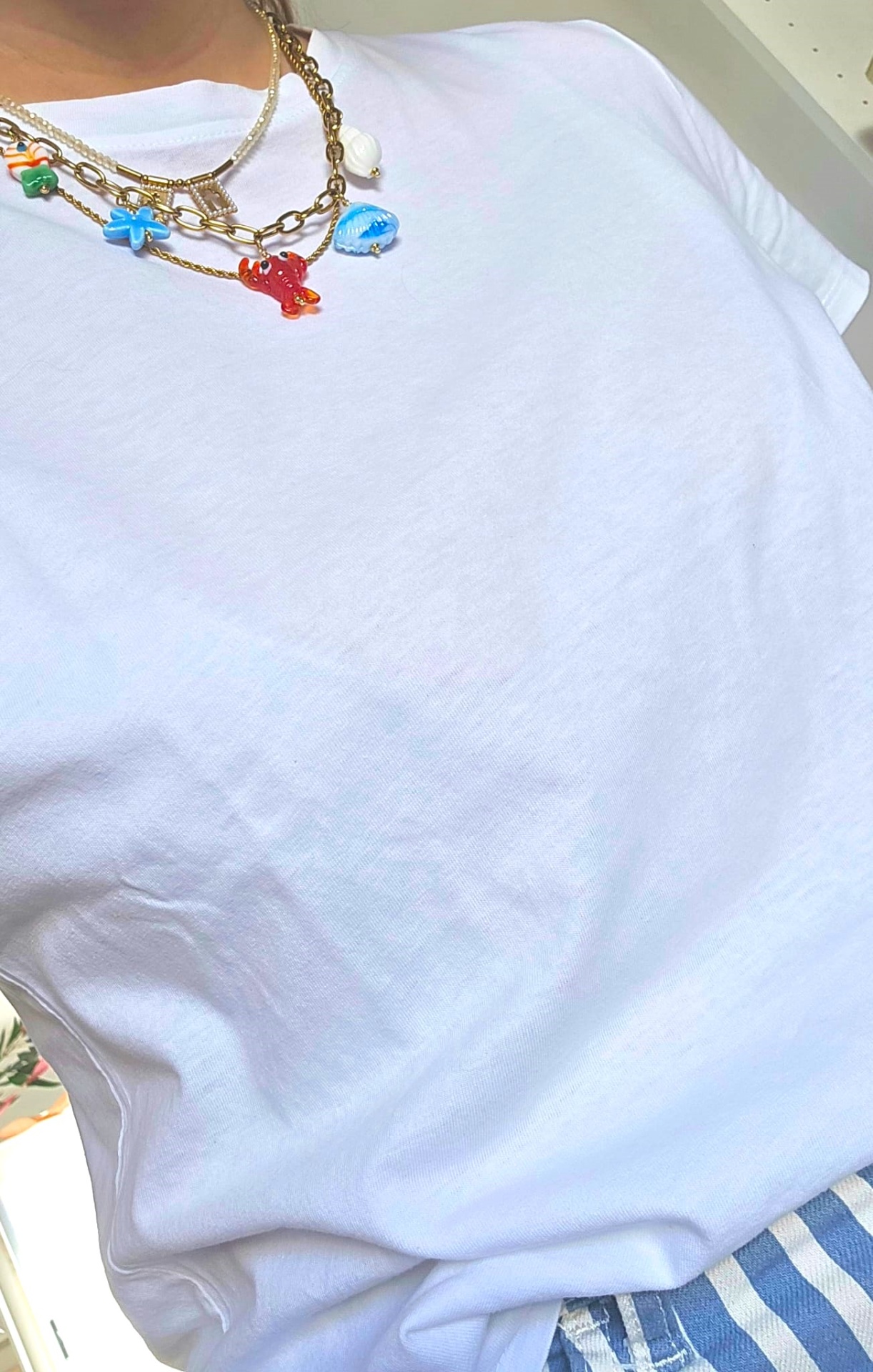 T-shirt branca com colares coloridos e calças riscas azul e branco