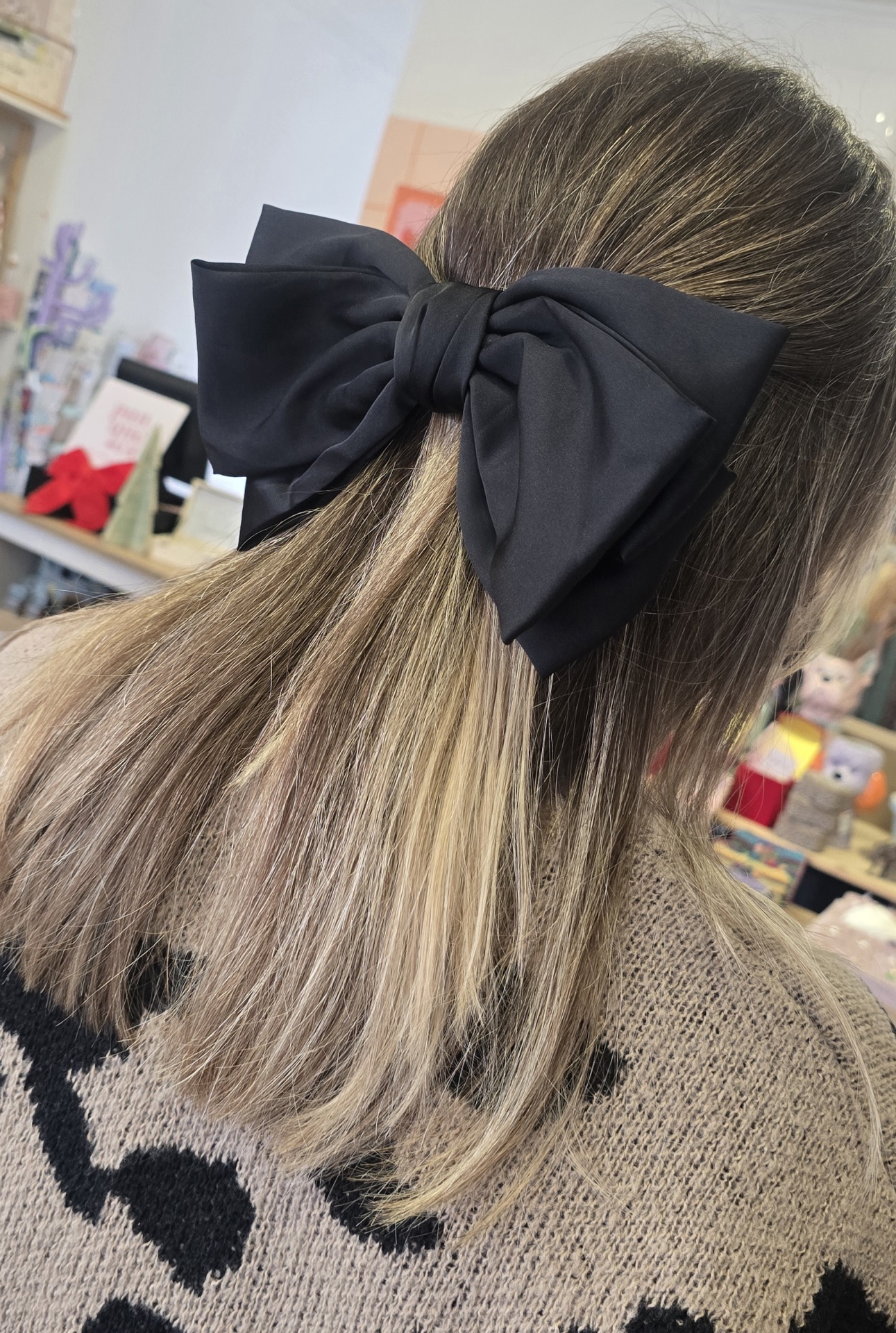 Laço de cabelo preto preso em cabelo castanho claro com fundo interno desfocado.