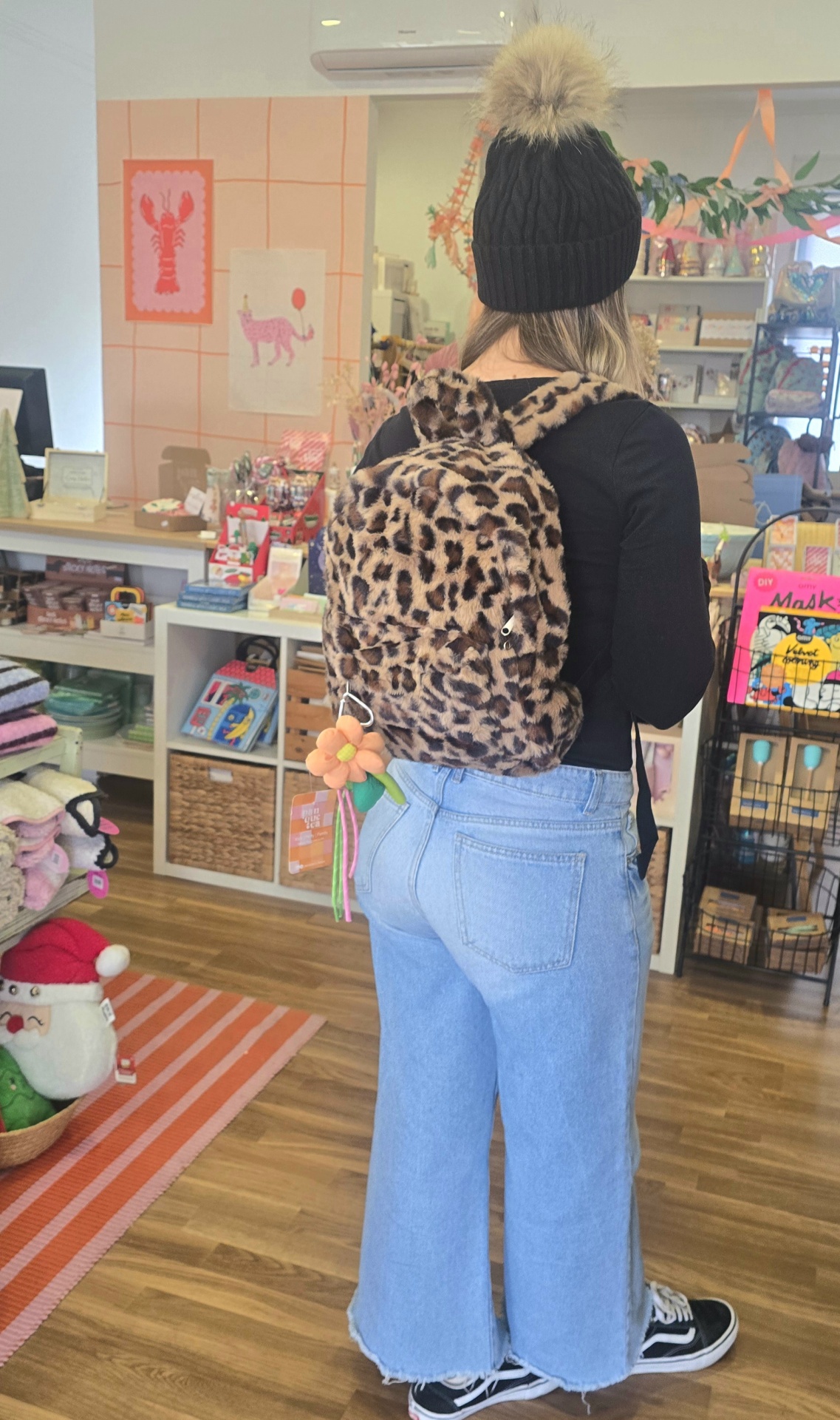 Mochila pelúcia padrão animal print usada por pessoa de costas numa loja