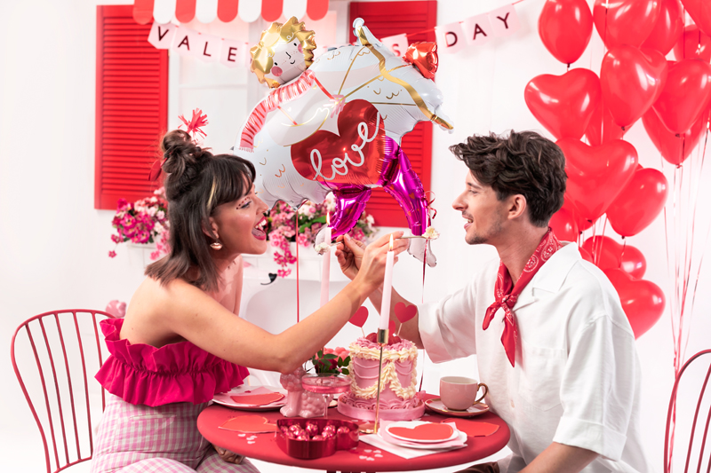 Casal com balões de festa em mesa decorada para Valentine's Day