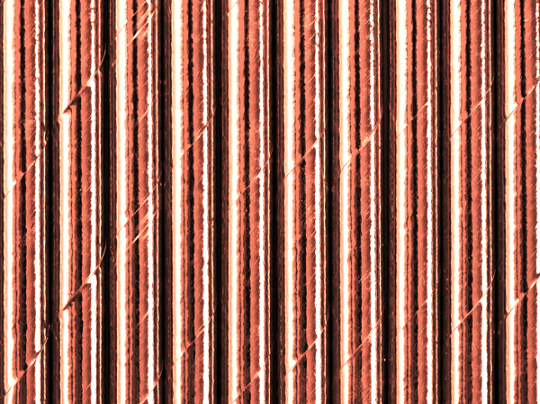 Superfície metálica com textura e linhas verticais em tons de cobre