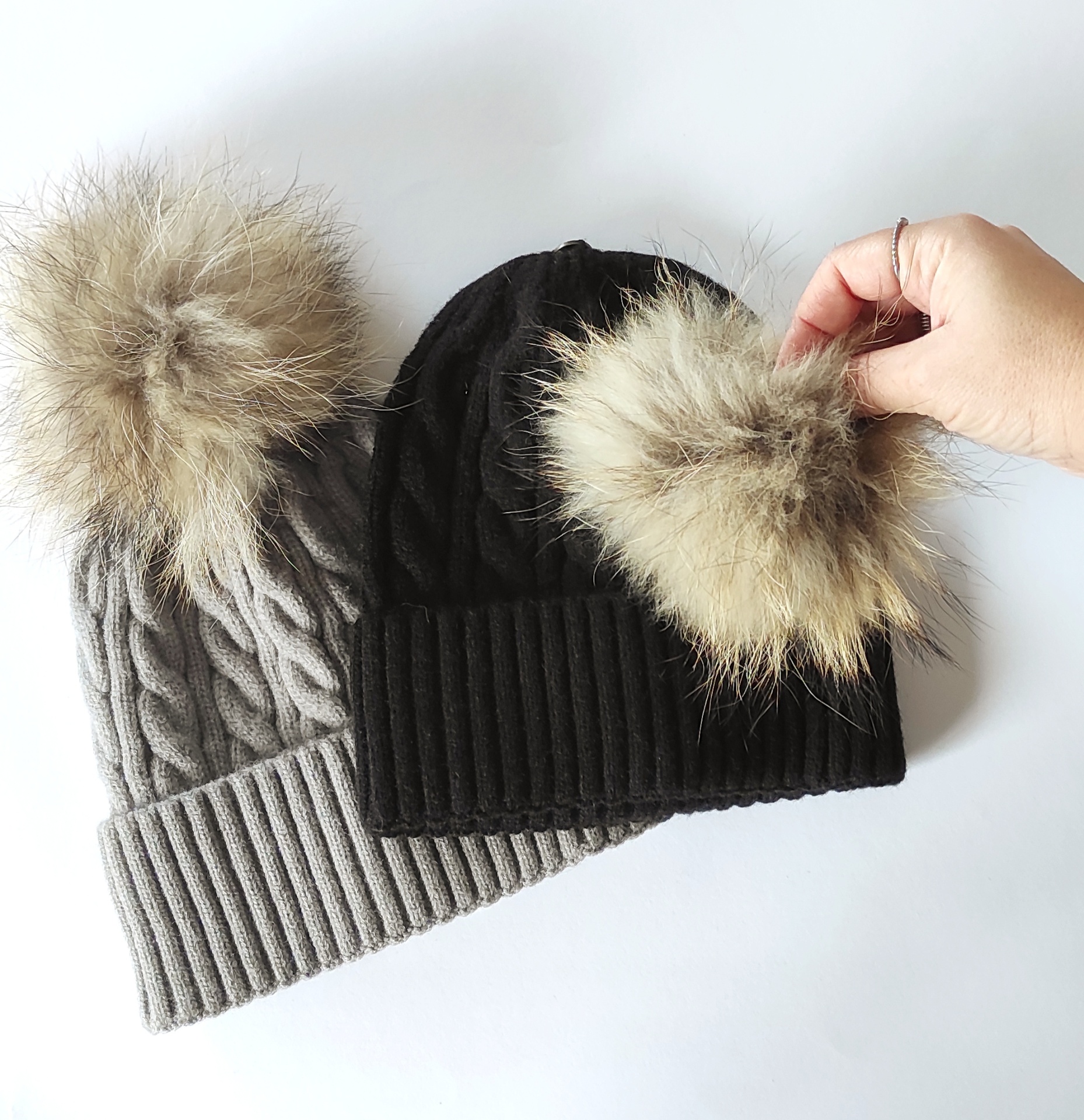 Dois gorros de malha, cinzento e preto, com pompom grande e felpudo