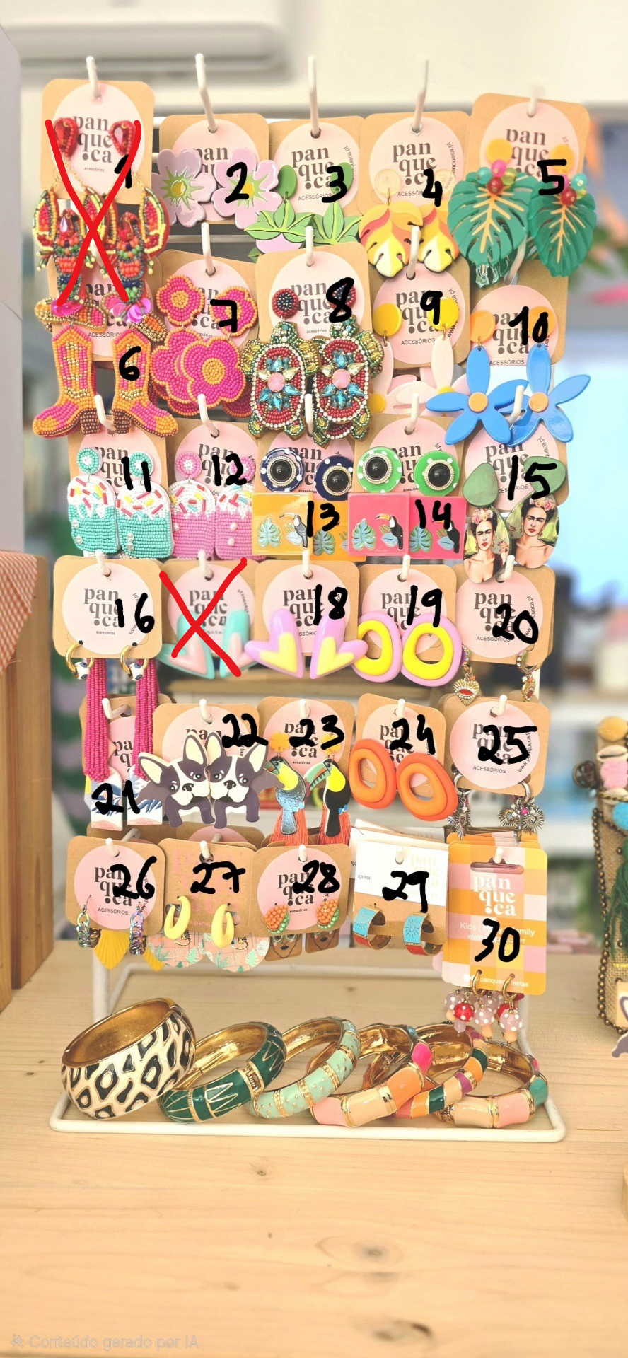 Expositor com brincos coloridos e pulseiras sobre mesa de madeira clara