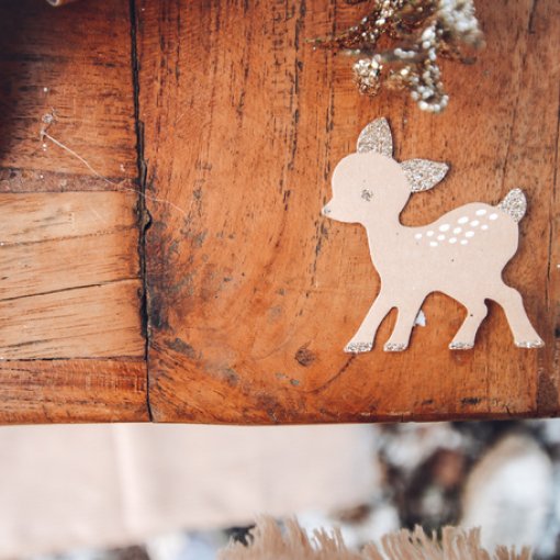 Figura decorativa veado castanho claro com glitter em superfície de madeira rústica