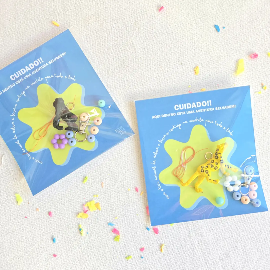 Dois conjuntos de brincos infantis em cartão azul com animais de plástico colorido e contas pastel