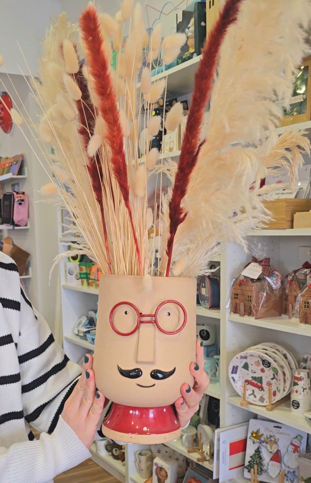 Vaso de cerâmica decorativo em formato de rosto com plantas secas