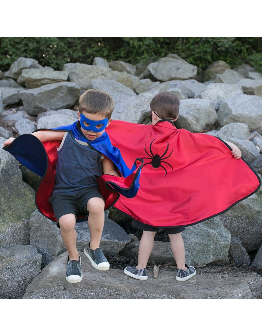 Crianças com capas de super-heróis e máscara azul entre rochas