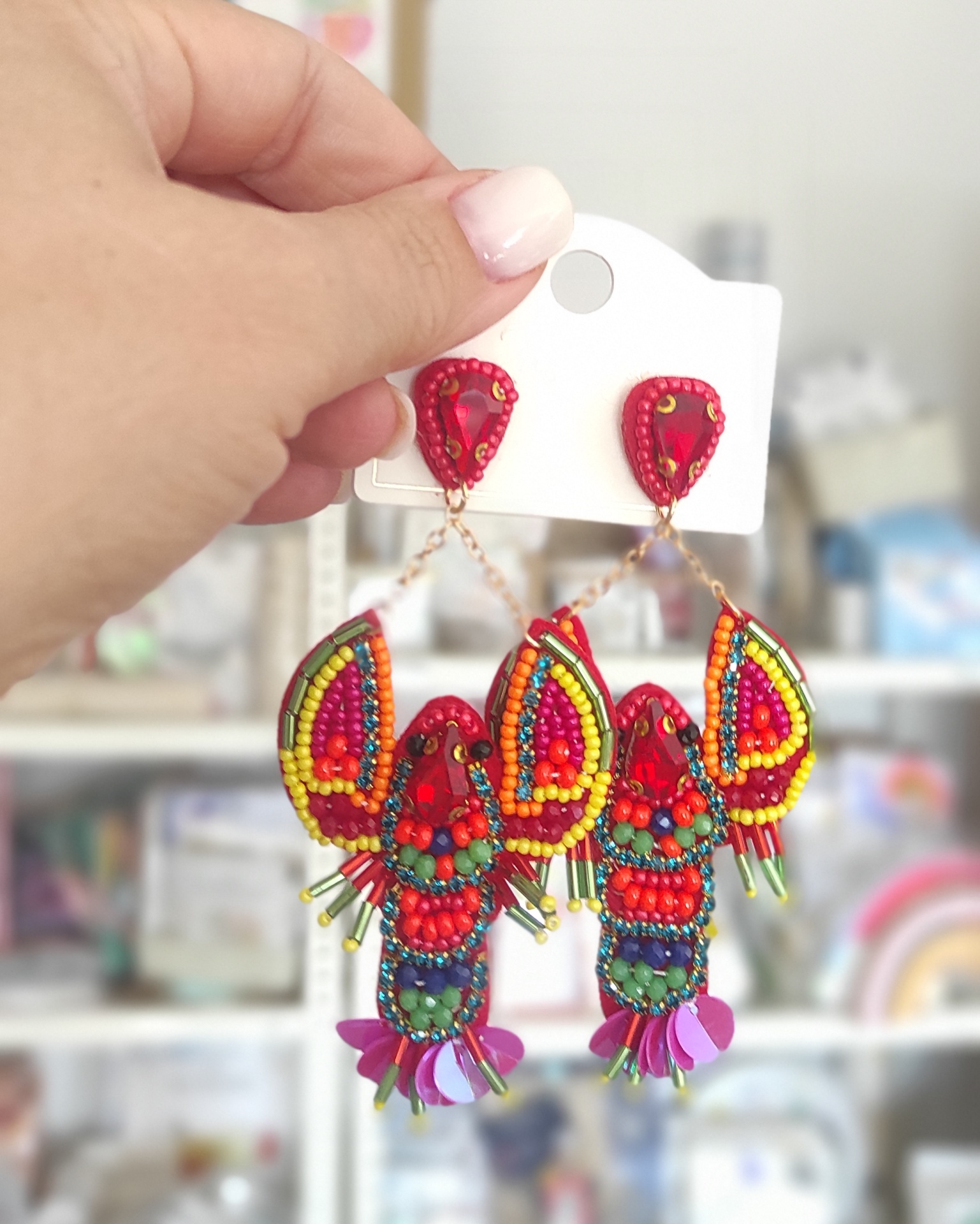 Brincos coloridos de miçangas com design geométrico pendurados em cartão branco