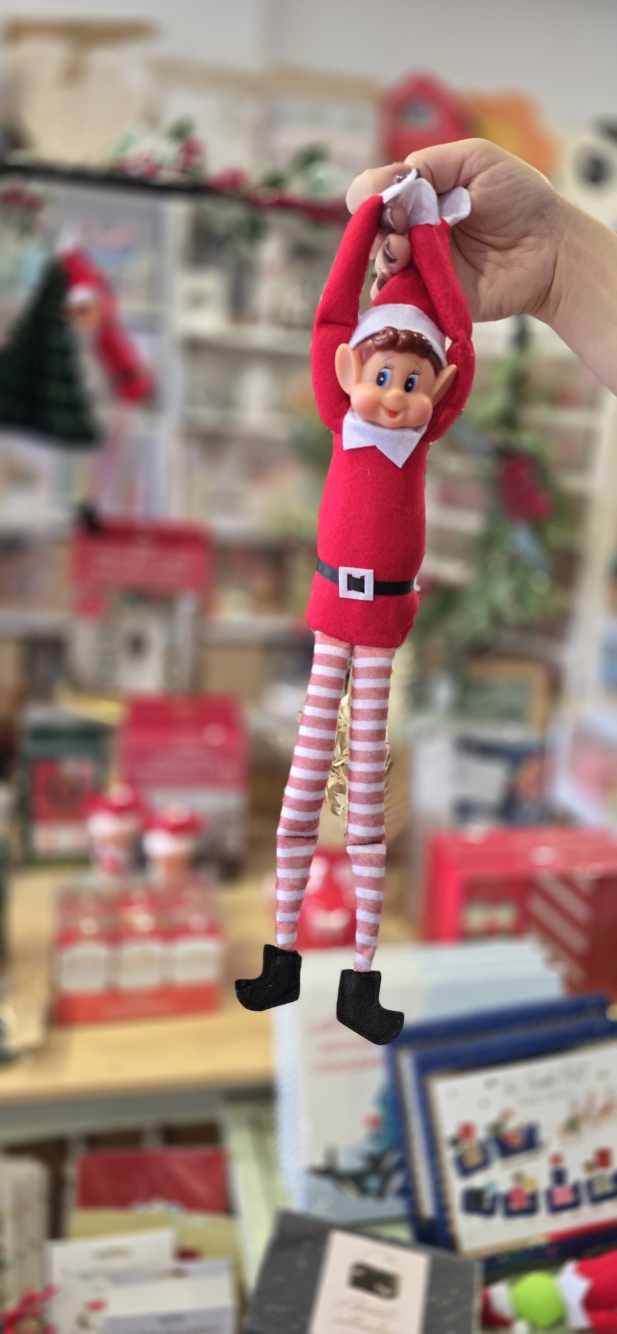 Boneco de elfo de Natal com roupa vermelha e branca, pernas listradas, botas negras e rosto sorridente