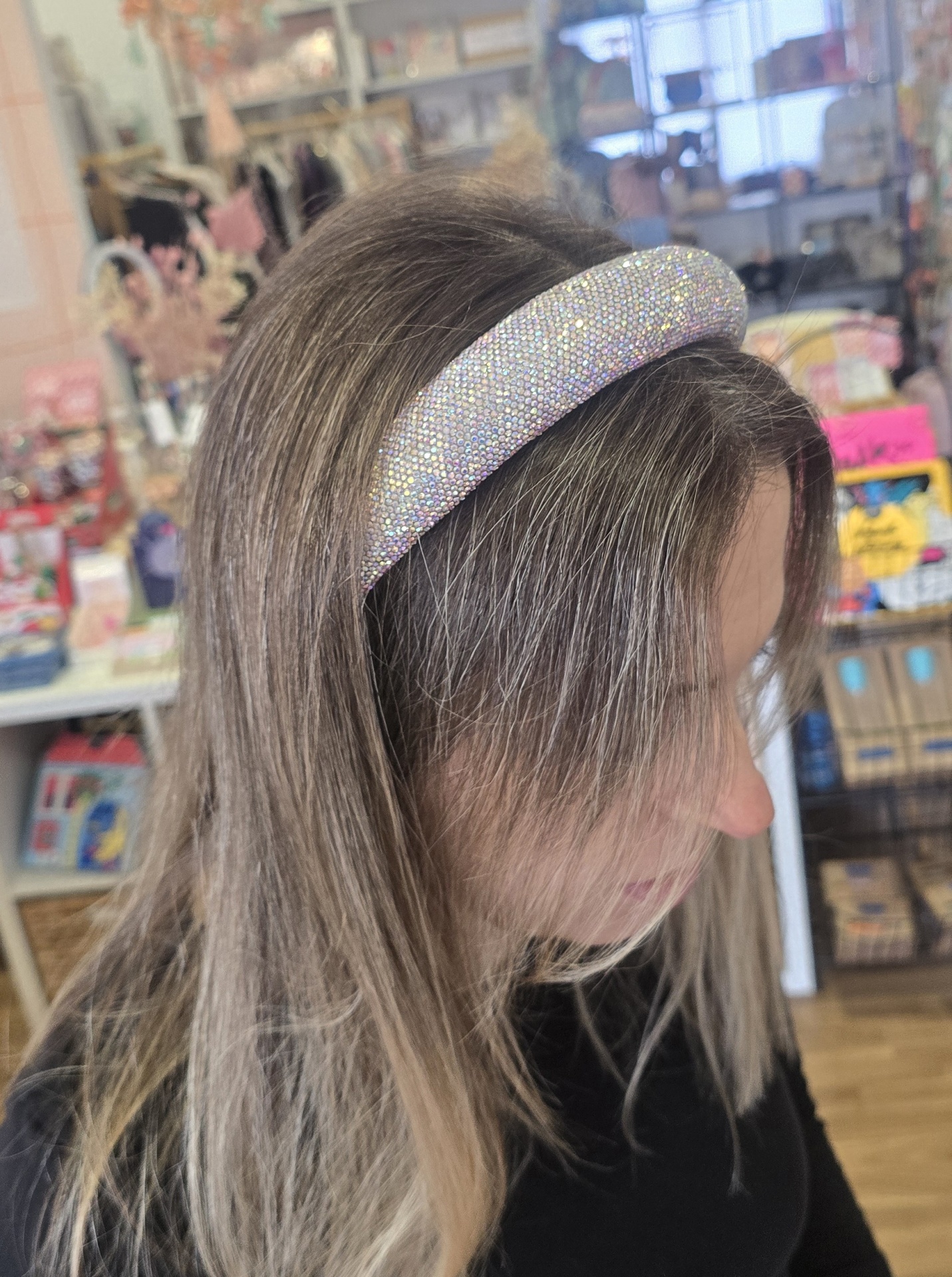 Faixa de cabelo espessa com pedras brilhantes prateadas usada numa mulher com cabelo loiro acinzentado