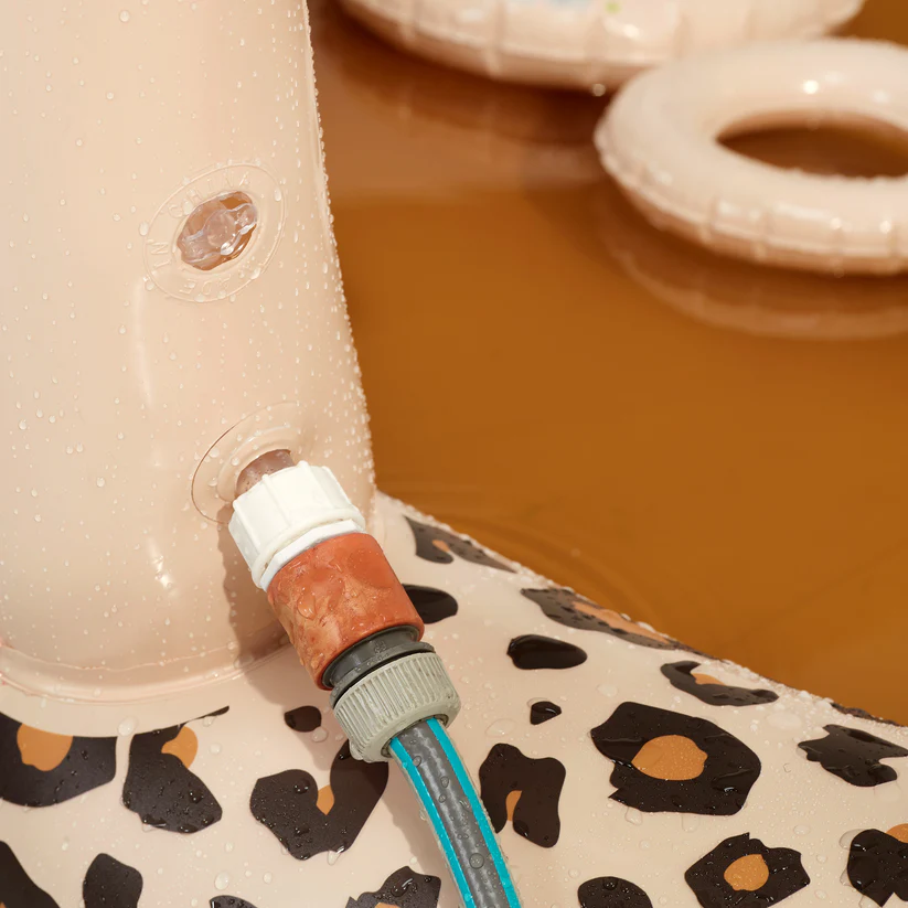 Detalhe de colchão insuflável com padrão de pele de cobra e ligação a mangueira em piscina.