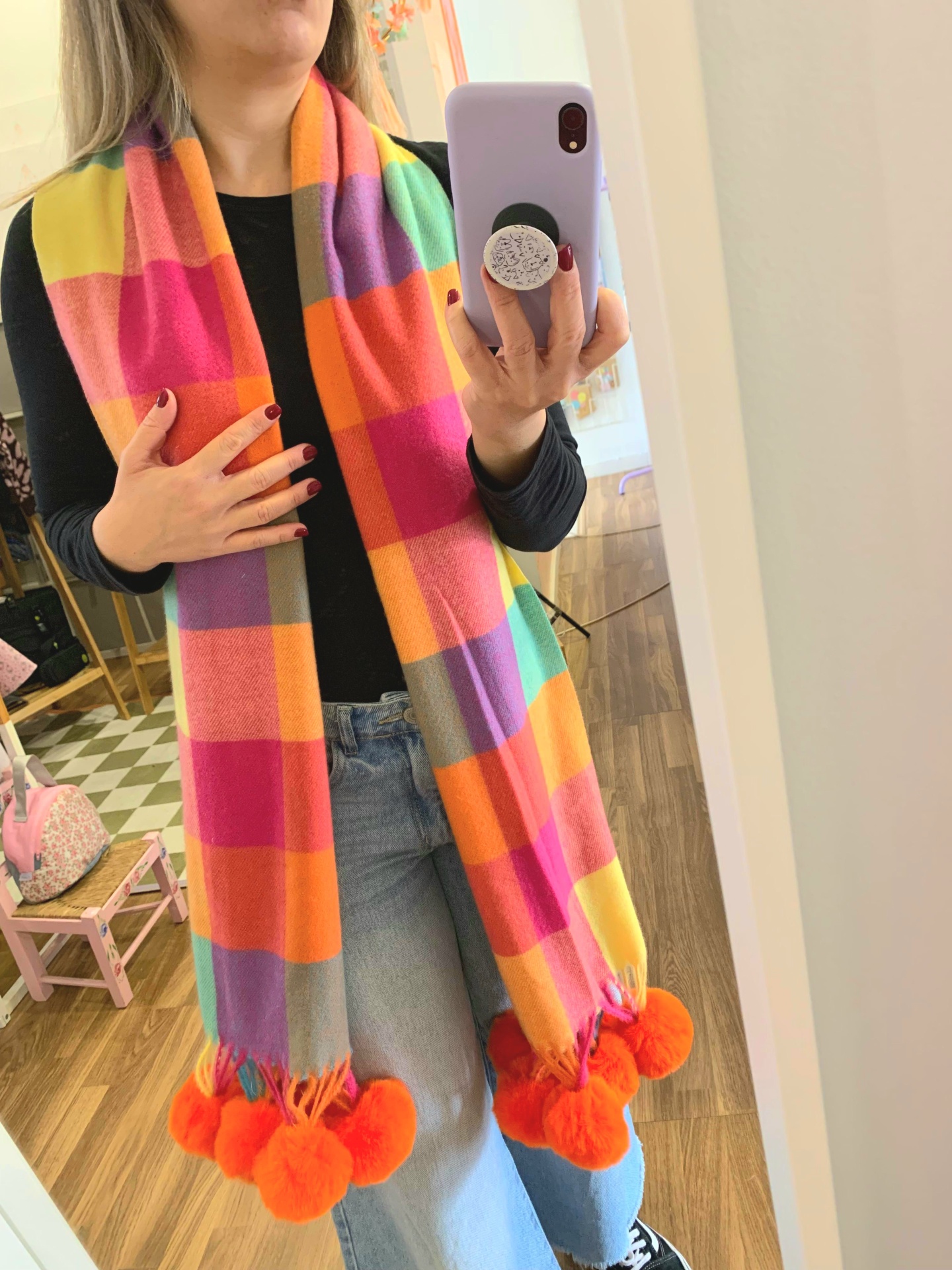 Cachecol colorido com padrão xadrez e pompons laranja