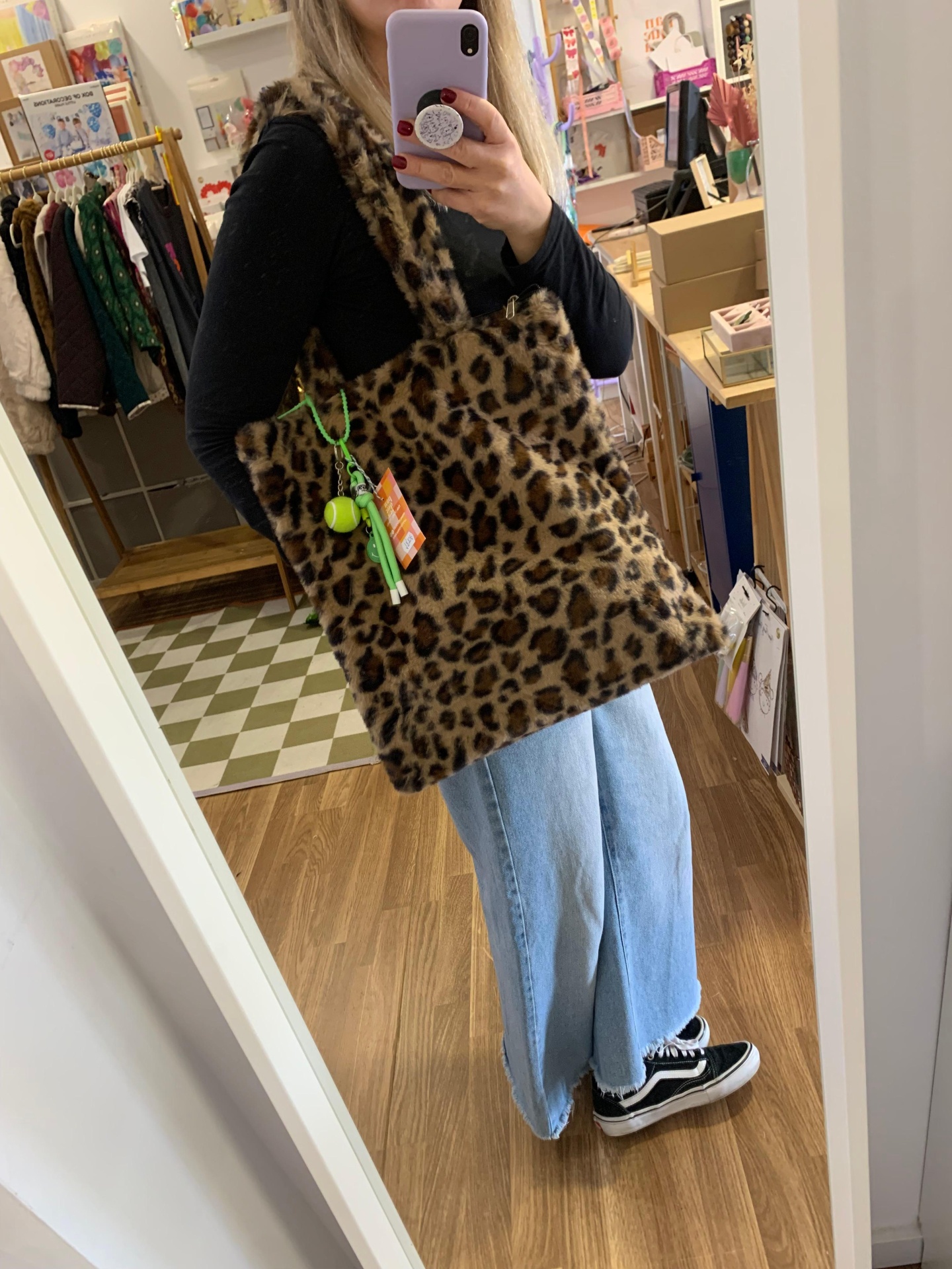 Mala tote pelo sintético padrão oncinha castanha e preta num interior de loja.