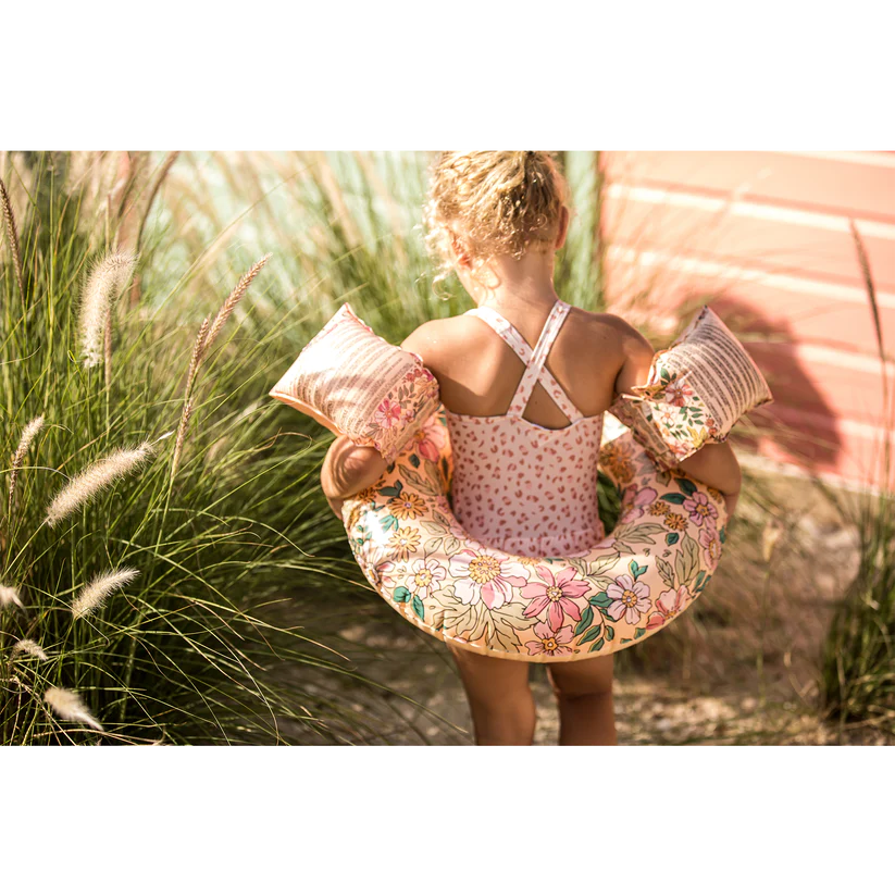 Criança com colete salva-vidas inflável floral e braçadeiras ao ar livre